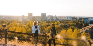 View of downtown Boise at sunrise from the foothills. Two young individuals are on a hike in the foreground.