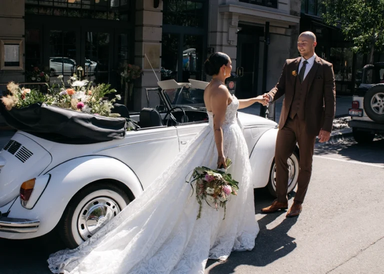 Bride and groom smiling, sitting on the bed of a boutique hotel room
