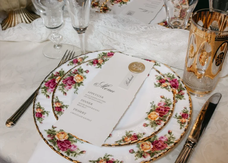Artisan cutlery sit upon a white intricate doily with a stamped paper atop.
